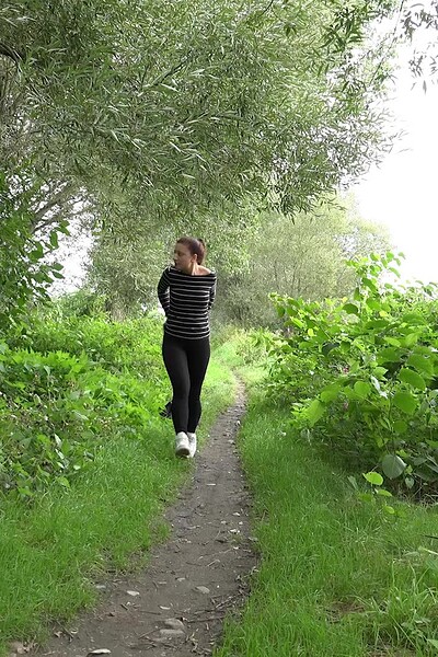 A cute brunette squats on the path and sprays her golden pee, leaving a large puddle.