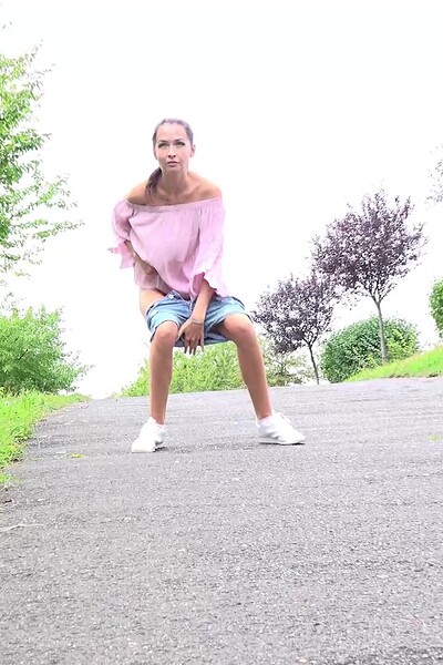 Mistica squats, holding her pussy as she pisses a stream onto the ground.