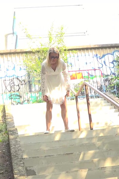 A hot blonde squats, lifts her dress, and pisses down the steps.