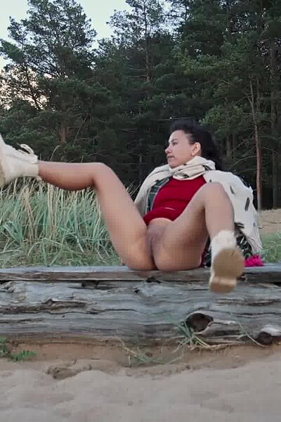 A gorgeous brunette lifts her red skirt, pulls off her panties, and is filmed pissing with her legs wide apart as the wind blows her stream back toward her face.