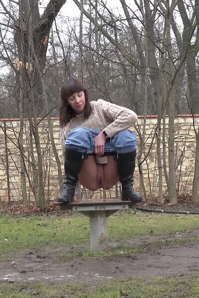 A brunette babe squats on a platform and releases a powerful stream of her piss.
