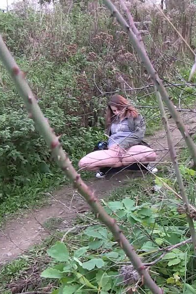 She squats, spreads her pussy lips, and pisses onto the soil.
